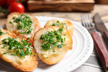 Fototapeta na wymiar Tasty bread slices with garlic and herbs on plate
