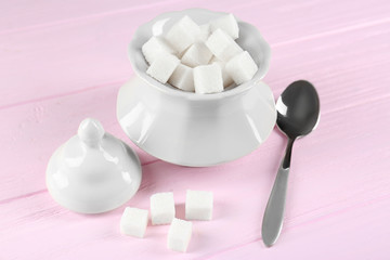 Sugar cubes with bowl and spoon on wooden table