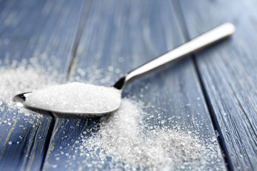 Spoon with sugar on table, closeup