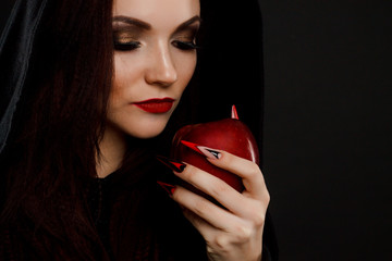 Stepmother witch gives poisoned red apple. Black background. horror fingernails