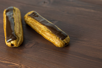 Two gorgeous asymmetric french chocolate eclairs on an ipe dark brown natural wood table