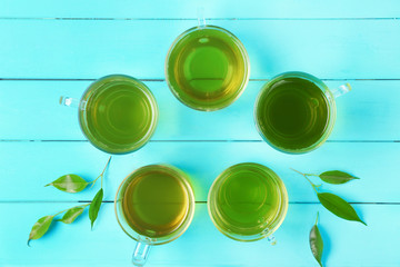 Cups of green tea on wooden background, top view