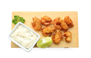 Wooden board with delicious coconut shrimps on white background