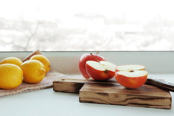 Wooden board with fresh apple cuts in half on windowsill