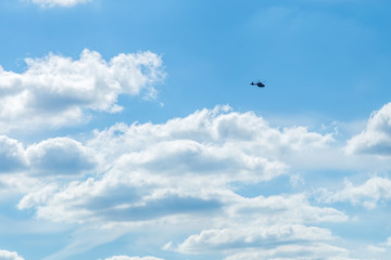 Fototapeta na wymiar Blue sky with sculpted clouds on the background with real tinny helicopter flying on the left side
