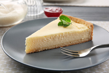 Plate with piece of tasty cheesecake on table, closeup