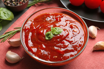 Delicious ketchup in bowl with ingredients on kitchen table, closeup