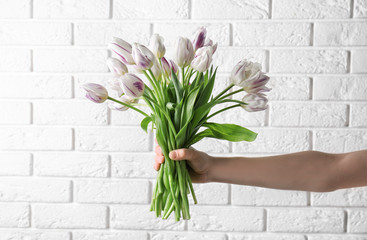 Woman holding beautiful bouquet of tulips on light background