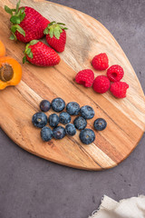 Wooden board with fresh organic fruit and berries