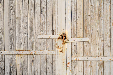Old wooden gate with peeling paint and loops for a padlock rusted