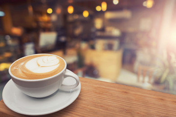 Cup of cappuccino on the table, coffee shop background, warm tone.