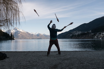 Fototapeta na wymiar A person juggles by the lake with a view of mountain