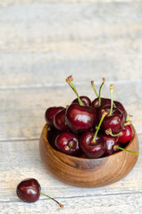 Cherry in a wooden cup on a concrete background vertically 