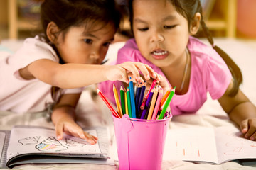 Two asian little girls  having fun to select the crayon for paint together in vintage color tone