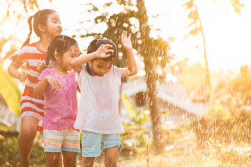 Asian children having fun to play with the rain together in the park in vintage color tone