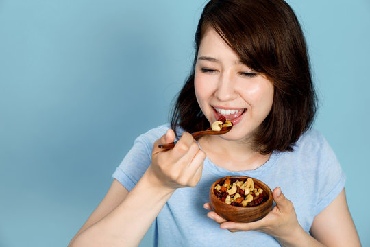 young woman eating granola on blue background. Macrobiotics concept. low carb diet. organic foods.