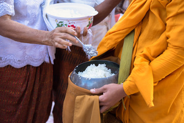Buddhist monk in south of Vietnam stand in a row waiting people put rice and food offerings in...
