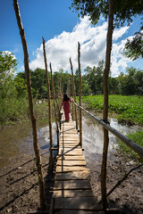 Wooden bridge connecting Champa village to river in Mekong delta, Vietnam. Champa girl walking on bridge