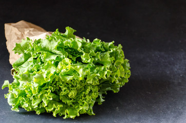 Lettuce in a paper bag on a dark marble background horizontally