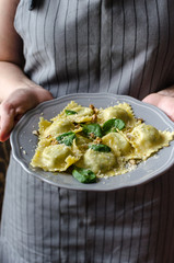 Italian ravioli with spinach and ricotta on a plate in hands