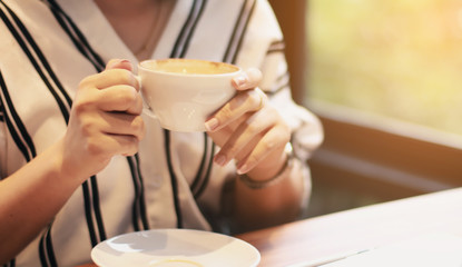 Get some rest. Cheerful delighted beautiful woman drinking coffee and working on the laptop while resting in the cafe