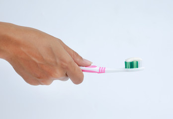 woman holding a toothbrush and placing toothpaste on it.