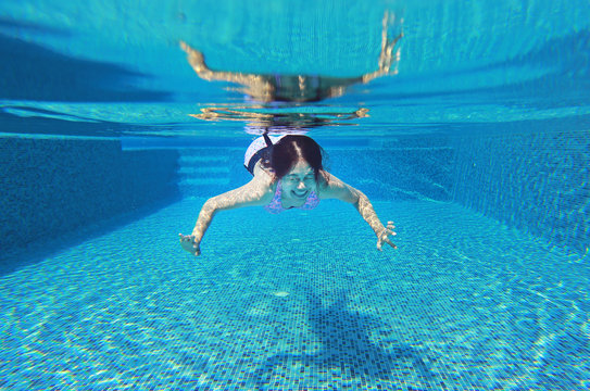 Underwater shot of young woman diving into the swimming pool.