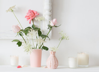 flowers in a vase and candles on white background