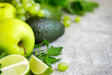 Selection of green vegetables and fruits on a gray concrete background closeup. Detox, dieting, vegetarian, fitness, healthy lifestyle concept.