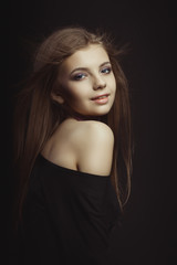 Naklejka premium Smiling young model in black dress posing at studio