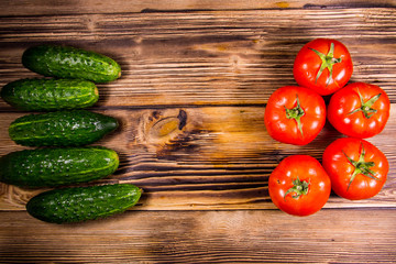 Fresh tomatoes and cucumbers on wooden table