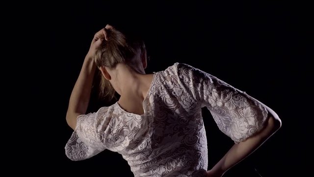 Young slender girl with her back to the camera moving gently lifting her hair and exposing the upper back vertebrae
