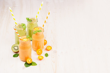 Freshly blended orange kumquat and green kiwi fruit smoothie in glass jars with straw, mint leaf,...