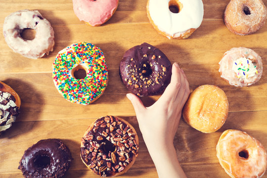 Person placing assorted colorful donuts