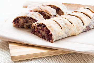 Apple strudel with cherries and raisins on cutting board