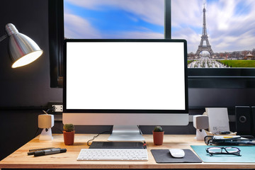 Graphic designer's workspace equipped with a pen tablet, a computer and white backgroud for text with beautiful Paris view city from the window