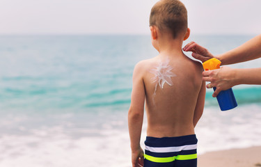 Little boy with suncream on shoulder at beach