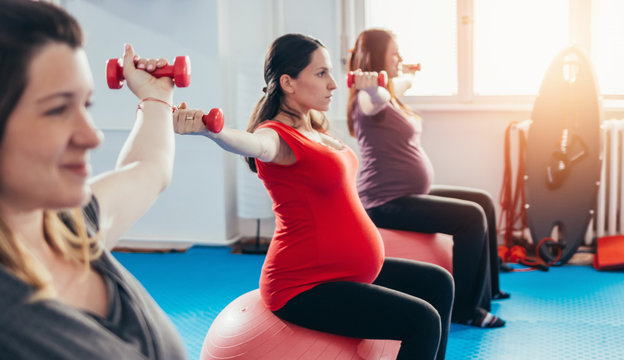 Group of pregnant women exercising and lifting weights feeling strong
