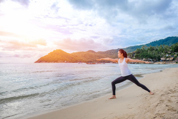 Fototapeta na wymiar Young beautiful woman practicing yoga on the beach at sunrise
