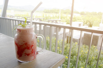 Glass of delicious strawberry smoothie with mint  on the wooden table background