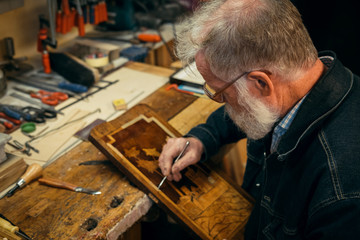 Senior wood carving professional during work