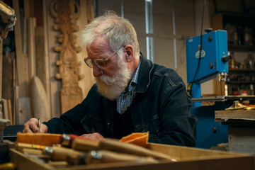 Senior wood carving professional during work