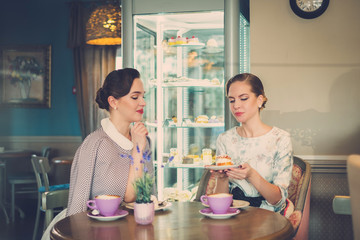 Two elegant young ladies in a cafe