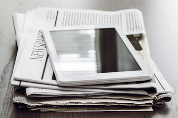 Newspaper and digital tablet on wooden table - obrazy, fototapety, plakaty