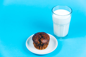 Cupcake and milk on blue background.