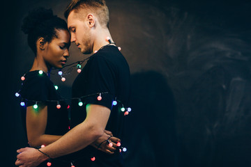 Tender love and happy relationships in the New Year's holiday. Young interethnic couple on a black...