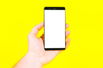 Touch screen mobile phone, in hand on yellow background.