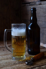 Mug of beer, bottle on wooden background. Photographed with natural light