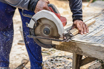 carpenter uses a circular saw to cut wood on the work area