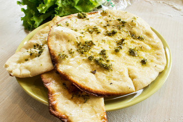 Freshly focaccia with olive oil, garlic and dill on the kitchen table. Selective focus.